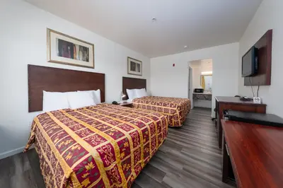 a hotel room with two beds and a flat screen tv at America Inn & Suites in Ridgecrest