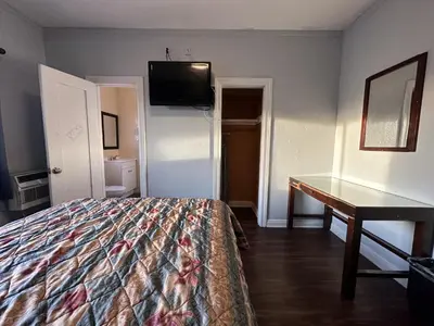 a bedroom with a bed and a desk and a television at Unity Hotel - No Parking & Rooms Are Upstairs in Long Beach