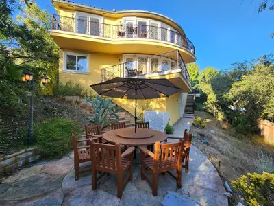 a table with chairs and an umbrella in front of a house at Hollywood Hills Hideout Apartment! in Los Angeles
