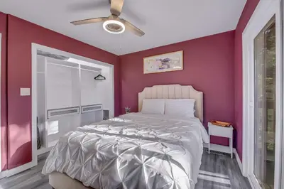a bedroom with a white bed and a red wall at Tree-Lined Lake Arrowhead Cabin about 1 Mi to Village! in Lake Arrowhead