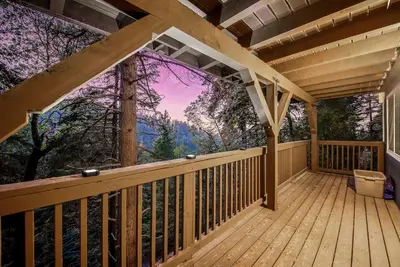 a wooden deck with a view of a forest at Tree-Lined Lake Arrowhead Cabin about 1 Mi to Village! in Lake Arrowhead