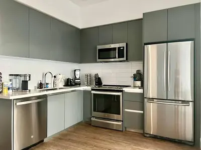 a kitchen with gray cabinets and stainless steel appliances at Luxe Corner Penthouse 1BR Condo on Sunset in Los Angeles