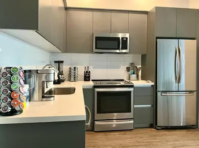 a kitchen with stainless steel appliances and a microwave at Luxe Corner Penthouse 1BR Condo on Sunset in Los Angeles