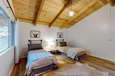 two beds in a room with a wooden ceiling at Ferndale woods in Running Springs