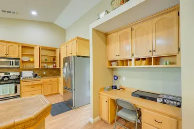 a kitchen with wooden cabinets and a stainless steel refrigerator at Porterville Getaway with Patio and Valley Views! in Porterville