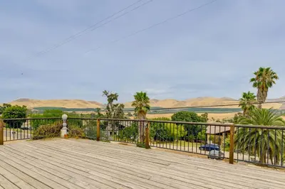 a wooden deck with palm trees and mountains in the background at Porterville Getaway with Patio and Valley Views! in Porterville