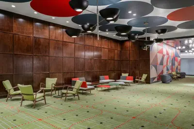 a lobby with chairs and tables and a ceiling at Hilton Buena Park Anaheim in Buena Park