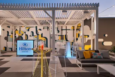 a living room with a hilton sign on the wall at Hilton Buena Park Anaheim in Buena Park