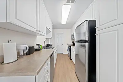 a kitchen with white cabinets and a stainless steel refrigerator at The Lilas-Ocean view Stay high floor Pool Parking in Los Angeles