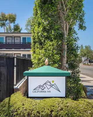 a sign for a park with a building in the background at California Inn in Anaheim