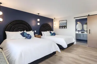 two beds in a bedroom with blue walls at California Inn in Anaheim