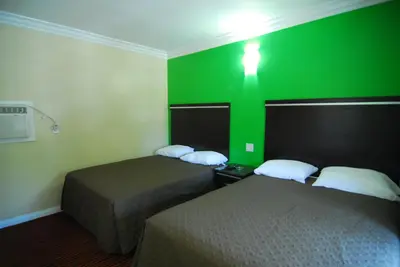 a room with two beds and a green wall at Studio City Inn - Near Universal Studios Hollywood in Los Angeles