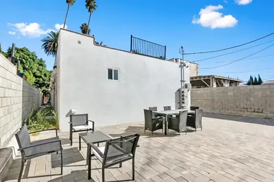 a patio with a table and chairs in front of a building at Muirfield Chic City Bungalow with Parking 1,2,3 in Los Angeles