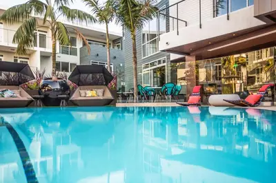 a swimming pool with chairs and palm trees in a building at Beverly Grove Chic City Oasis 2 BR Apt with Den 138 in Los Angeles