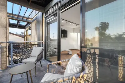 a balcony with a couch and a chair and a table at NEW Luxury Concrete Home Just Minutes from the Beach in Long Beach