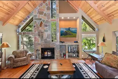 a large living room with a stone fireplace at Arrowhead Lake Cabin pool table stunning views in Lake Arrowhead