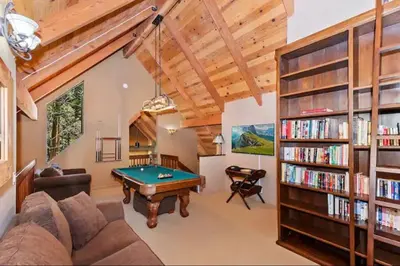 a living room with a pool table and bookshelves at Arrowhead Lake Cabin pool table stunning views in Lake Arrowhead