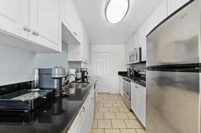 a kitchen with white cabinets and a stainless steel refrigerator at Garnet Glow Full Ocean and Venice Beach view 3BR in Los Angeles