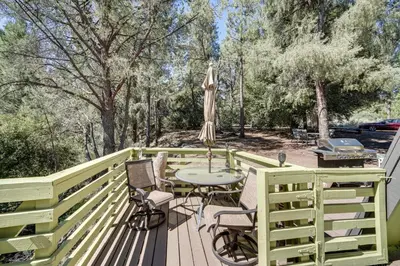 a wooden deck with a table and chairs on it at Modern Pine Mountain Club Cabin with Community Pool! in Pine Mountain Club