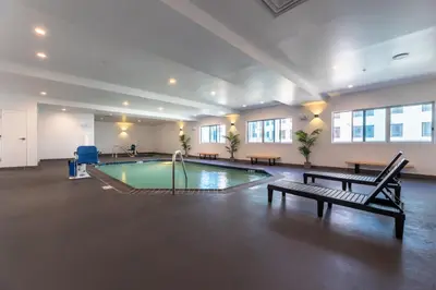 a pool in a large room with a bench and a table at Hotel Mai Downtown Long Beach in Long Beach
