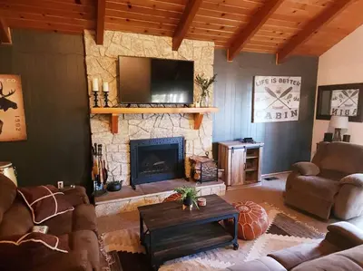 a living room with a fireplace and a tv at The Ponderosa in Running Springs