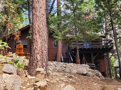 a log cabin in the woods with a tree at The Ponderosa in Running Springs