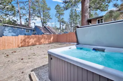 a hot tub in a backyard with a fence at Storyville Hot Tub- Arcade- Walk To Marina Cabin in Big Bear Lake