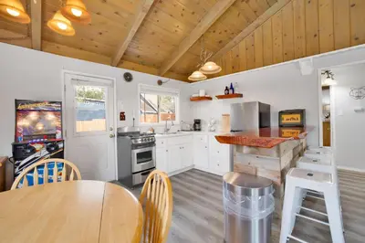 a kitchen with white cabinets and a wooden ceiling at Storyville Hot Tub- Arcade- Walk To Marina Cabin in Big Bear Lake