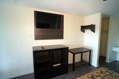 a room with a tv on the wall and a table at Airport Stay Motel in Ontario