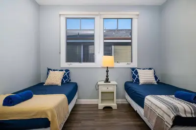 two beds in a room with two windows at Comfy 4BR home near Korea Town in Los Angeles