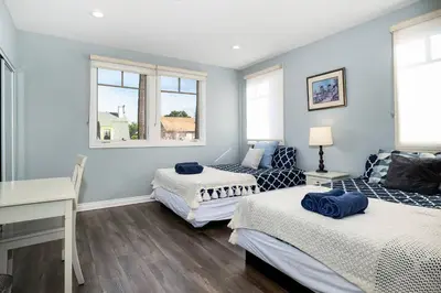 two beds in a room with blue walls and windows at Stylish 4 BR house near Korea Town (Central LA) in Los Angeles