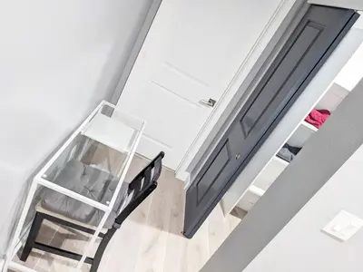 an open stairway with a black door and a chair at Lucky Charm 4 Bedroom Mid-City Apartment in Los Angeles