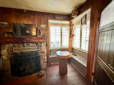 a living room with a stone fireplace and a television at Boulder Bay Cottages in Big Bear Lake