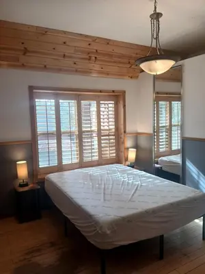 a large bed in a bedroom with two windows at Boulder Bay Cottages in Big Bear Lake