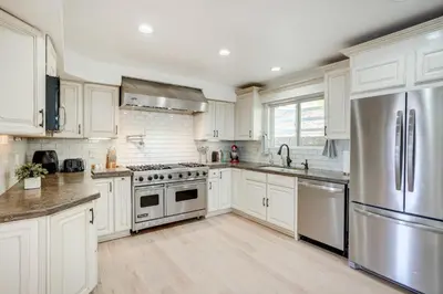 a kitchen with white cabinets and a stainless steel refrigerator at Chic Santa Paula Home with Mountain and City Views! in Santa Paula