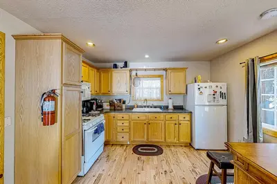 a kitchen with wooden cabinets and a white refrigerator at Heliotrope Hideaway in Lake Arrowhead