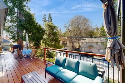 a balcony with a couch on a wooden deck at Heliotrope Hideaway in Lake Arrowhead