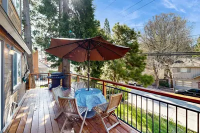 a table and chairs on a deck with an umbrella at Heliotrope Hideaway in Lake Arrowhead
