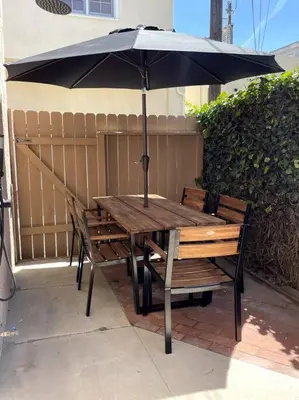 a wooden table and chairs with an umbrella at Huge Updated Spanish Apt - Steps to Beach & Bay! in Long Beach