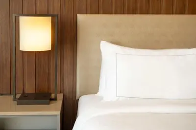 a bedroom with a bed with a white pillow and a lamp at DoubleTree by Hilton San Bernardino in San Bernardino