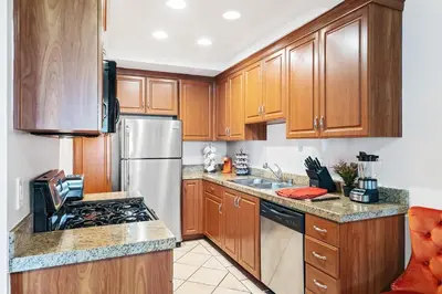 a kitchen with wooden cabinets and a stainless steel refrigerator at Beverly Hills 2 bed 2 bath Penthouse with Den and Parking 414 in Los Angeles