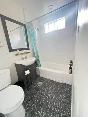 a bathroom with a toilet and a sink and a tub at Little Bettys Cottage in Torrance