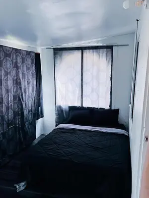 a bedroom with a black bed and a window at Zen Home in Santa Ana