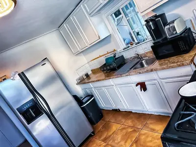 a kitchen with white cabinets and a stainless steel refrigerator at Zen Home in Santa Ana