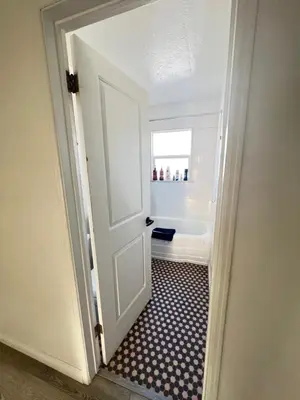 a bathroom with a door leading to a bath tub at Little Betty’s Hideaway in Torrance