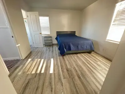 a bedroom with a bed and a wooden floor at Little Betty’s Hideaway in Torrance