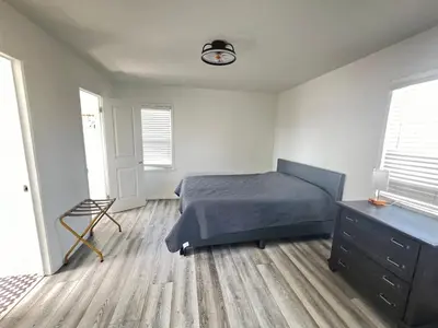 a bedroom with a bed and a dresser and two windows at Little Betty’s Hideaway in Torrance