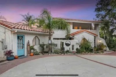 a large white house with a palm tree at Boho Chic Malibu Retreat Estate Salt Pool + Yoga in Malibu