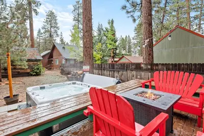 a backyard with a hot tub and two red chairs at Mountain Getaway in Big Bear Lake
