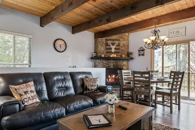 a living room with a leather couch and a fireplace at Panoramic Views at Deer Crest Lodge in Lake Arrowhead